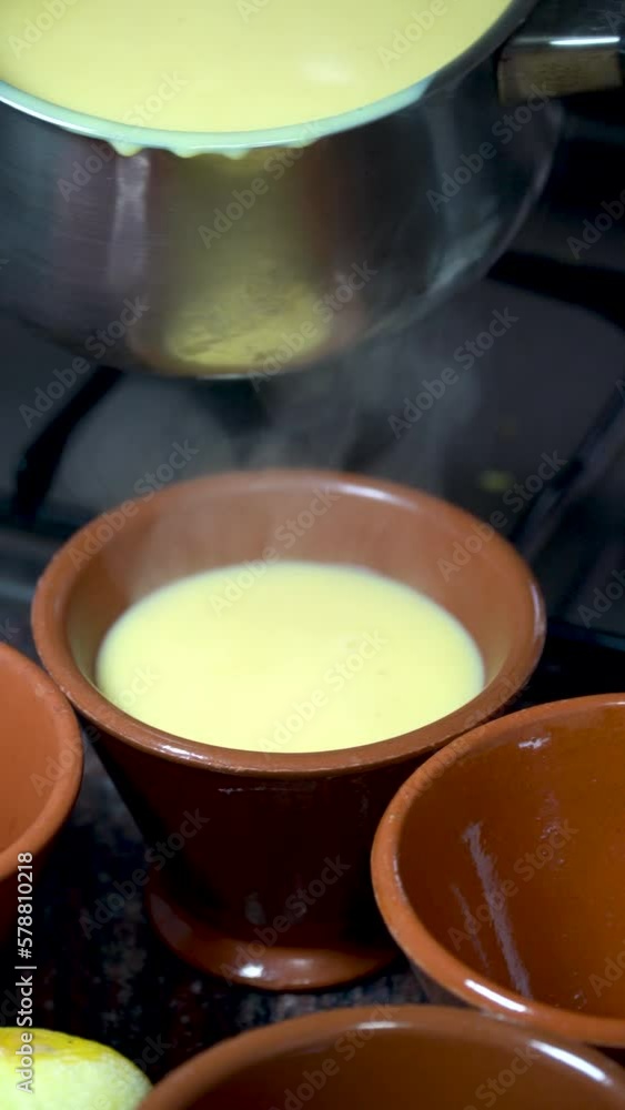 Close up, a person serves homemade hot custard in ceramic bowls. Close up, a person serves homemade hot custard in ceramic bowls.