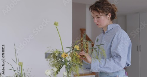 female doing new bouquet. Girl working in flower shop studio. Female florist artist cleans flowers for a beautiful bouquet, workplace view. High quality 4k footage