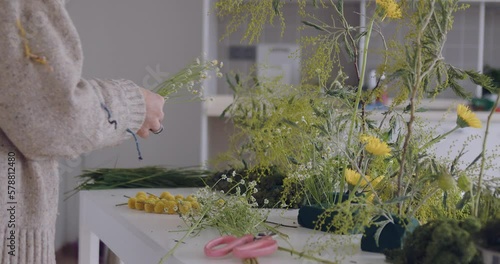 female doing new bouquet. Girl working in flower shop studio. Female florist artist cleans flowers for a beautiful bouquet, workplace view. High quality 4k footage