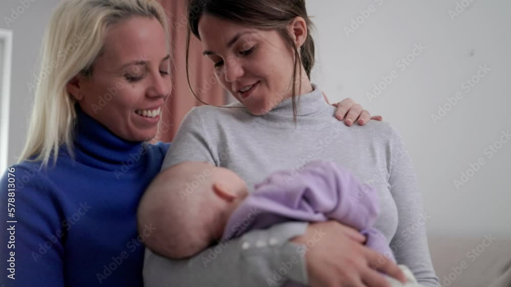 Authentic gay lesbian couple of mothers and newborn baby having tender moment at home - Lgbt family concept Authentic gay lesbian couple of mothers and newborn baby having tender moment at home - Lgbt family concept