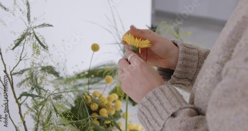 female doing new bouquet. Girl working in flower shop studio. Female florist artist cleans flowers for a beautiful bouquet, workplace view. High quality 4k footage
