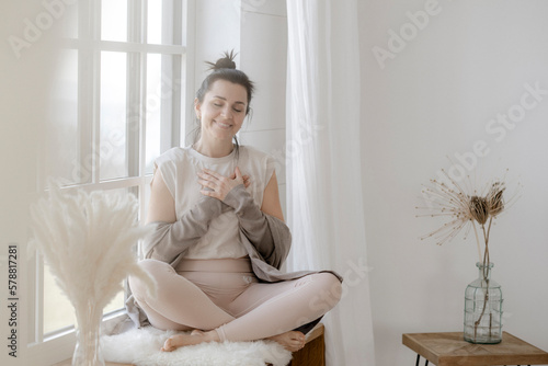 Zufriedene Frau sitzt dankbar am Fenster photo