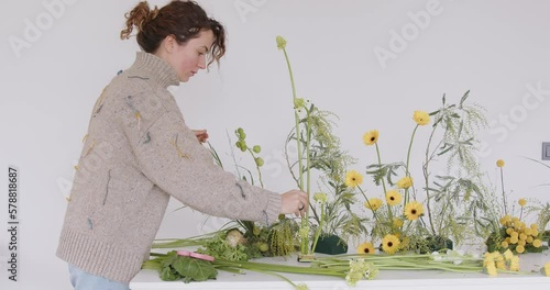 female doing new bouquet. Florist makes a floral oasis. Girl working in flower shop studio. Female florist artist cleans flowers for a beautiful bouquet, workplace view. High quality 4k footage