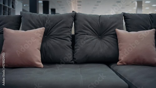 A gray sofa, shot close up, with gray and beige decorative pillows. Homedecor concept, minimalist. 4k slow motion video.