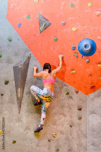 Young Woman Climber Bouldering in Climbing Gym. Extreme Sport and Indoor Climbing Concept