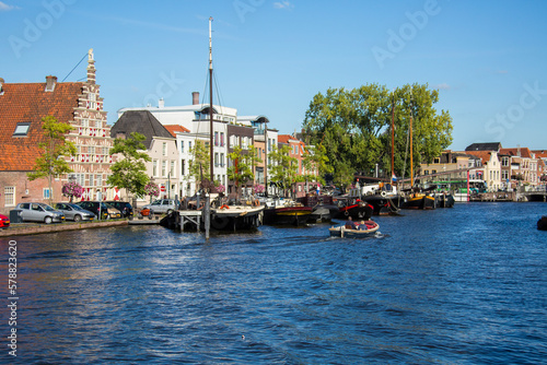 small dutch ship port in statt with small moving boats in the front and houses in the background photo