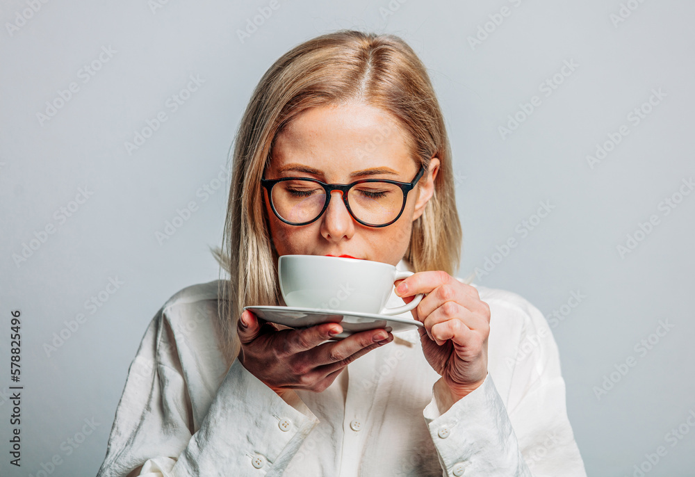 Portrait of beautiful blonde in white shirt with cup of coffee on white background