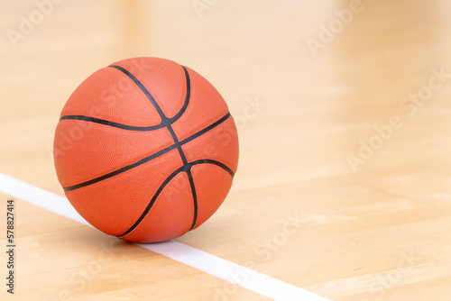Orange basketball ball on hardwood court floor. Horizontal sport theme poster, greeting cards, headers, website and app