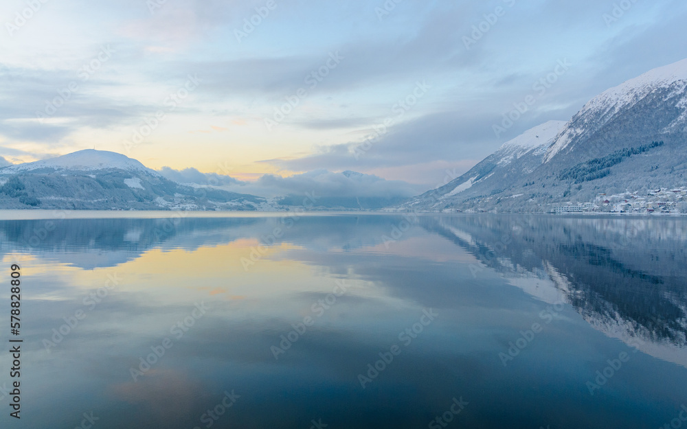 reflection in fjord with sun behind clouds