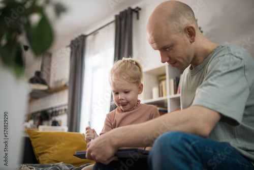 People with cochlear implant system. Kid study to hear with her father, learning with video on tablet. Installation cochlear implant on child girl ear for restores hearing.