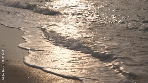 夕日に照らされて輝く沖縄の海の波打ち際