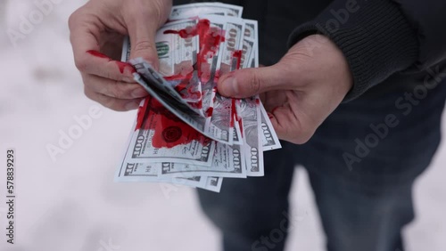 Blood on cash, Illegal earnings, Dirty money. A pile of money stained with blood is being counted by a man's hands. photo