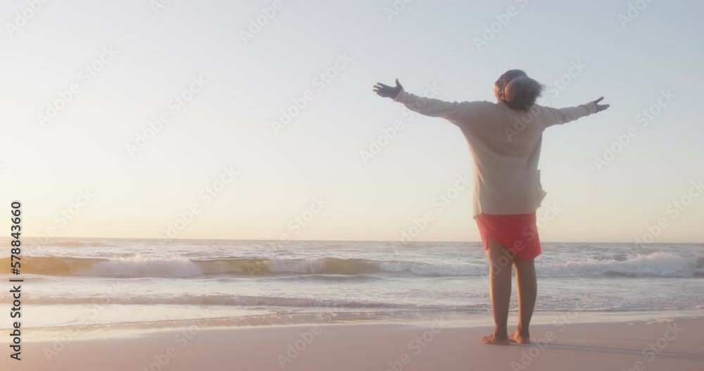 Happy senior african american woman widening arms at beach, in slow motion, with copy space Happy senior african american woman widening arms at beach, in slow motion, with copy space