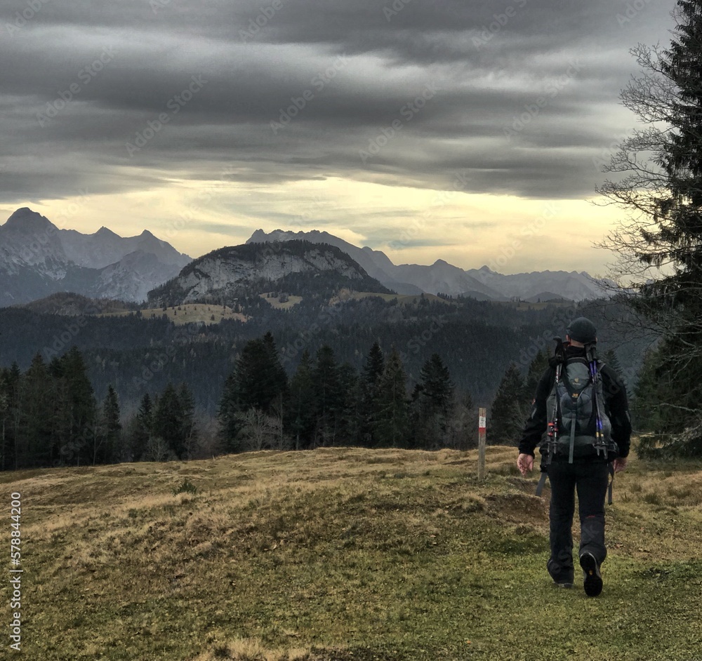 Fototapeta premium Wanderer von hinten an einem bewölkten Tag im Herbst vor einer beeindruckenden Bergkulisse im Heutal, Alpen, Tirol, Österreich