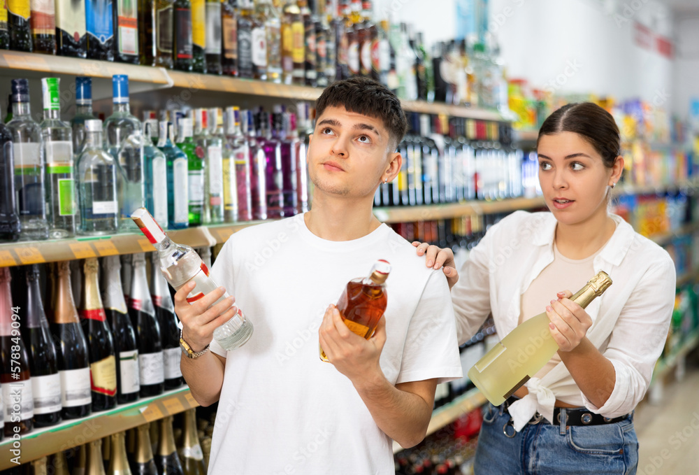 in alcohol department of store, young spouses argue over choice of alcoholic drink