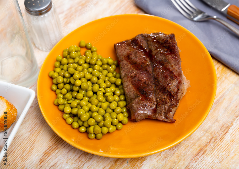 Fried beef cutlet with green peas on a plate