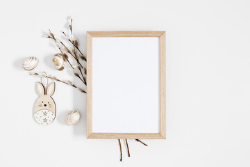 Easter trendy composition. Photo frame top view, willow plant branches, easter eggs and bunny on white background. Minimal concept Easter. Flat lay, top view, copy space