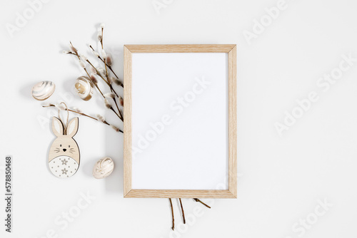 Easter trendy composition. Photo frame top view, willow plant branches, easter eggs and bunny on white background. Minimal concept Easter. Flat lay, top view, copy space