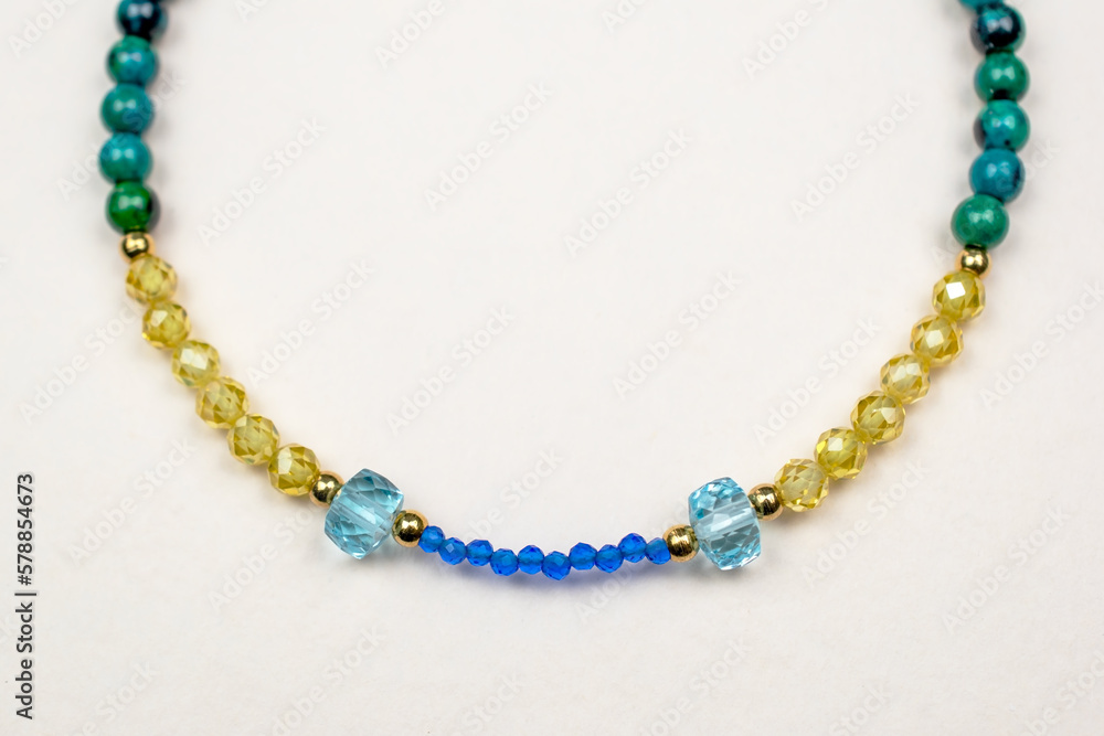 Colorful gemstone crystal beads necklace on white, unique handmade jewelry background Colorful gemstone crystal beads necklace on white, unique handmade jewelry background