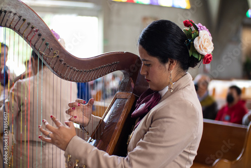 mariachi woman harpist in a chirch fun, hispanic female playing harp traditional mexican music photo