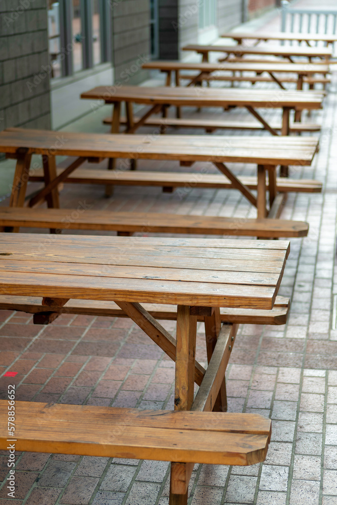 Picnic bench with cement tiles and brick floor made of wood and timber in front of restaurant and business in city Picnic bench with cement tiles and brick floor made of wood and timber in front of restaurant and business in city