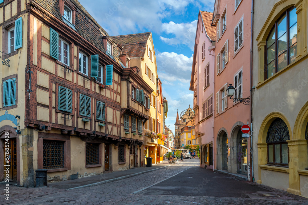 A tourist train appears in the distance in the historic medieval center of Colmar, France, one of the main stops along the Alsatian wine route.