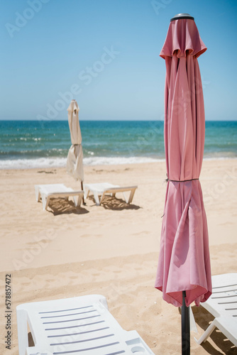 Fototapeta Naklejka Na Ścianę i Meble -  Due ombrelloni chiusi su una spiaggia portoghese deserta e le sdraio vuote