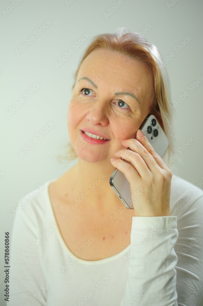 Woman talking by mobile phone at home Close-up portrait of smiling adult woman talking by phone and looking away Woman talking by mobile phone at home Close-up portrait of smiling adult woman talking by phone and looking away