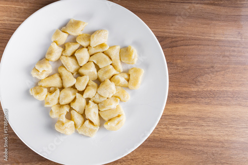 BAKED GNOCC IN A WHITE PLATE ON A WOODEN BACKGROUND.