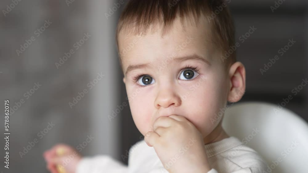 Adorable grey-eyed Caucasian child eating something and smiling sweetly. Close up portrait. Blurred backdrop. Adorable grey-eyed Caucasian child eating something and smiling sweetly. Close up portrait. Blurred backdrop.