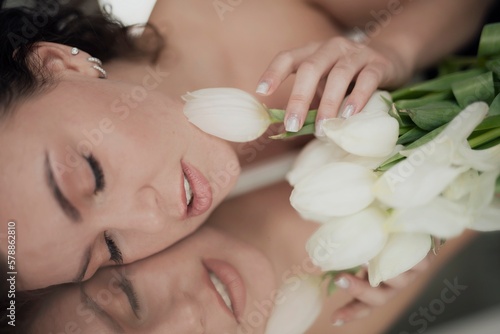 Portrait of young beautiful woman with curly hair and tulips, in mirror reflection