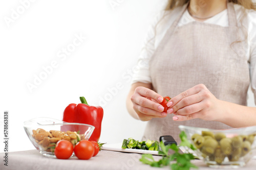 Beautiful young woman preparing vegetable salad in the kitchen. Healthy food. Vegan salad Diet concept. Healthy lifestyle. Cook at home. Prepare food close-up  only hands  olives  tomato  cucumber