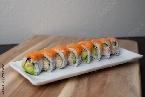 California sushi roll topped wit salmon. Japanese traditional dishes combine with American ingredients.