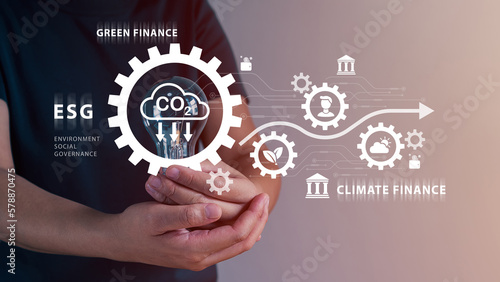 Person hand holding light bulb with green financial, finance and business industry, climate finance, environmental, social, governance, ESG, carbon credit, net zero, digital money, virtual screen.
