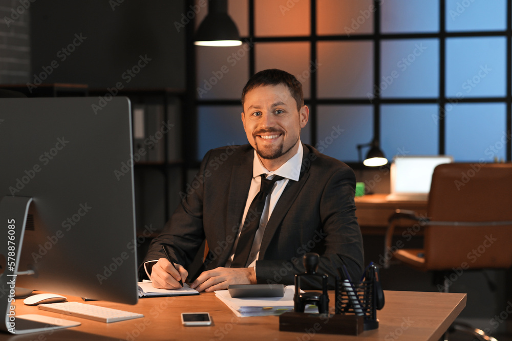 Male accountant working with notebook in office at night Male accountant working with notebook in office at night