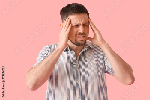 Stressed young man in shirt on pink background