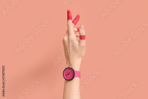 Woman with painted fingers and stylish wristwatch on pink background