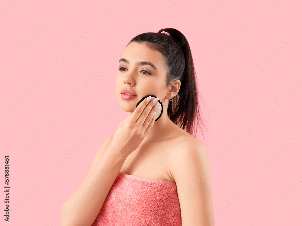 Young woman removing makeup with cotton pad on pink background Young woman removing makeup with cotton pad on pink background