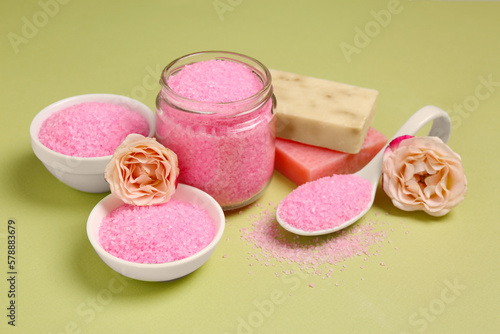 Aromatic sea salt and beautiful flowers on pale green background
