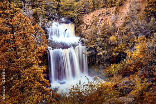 waterfall in mountain surrounded by golden trees in autumn