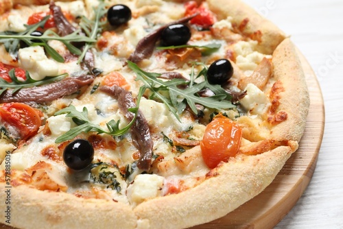 Tasty pizza with anchovies, arugula and olives on white wooden table, closeup