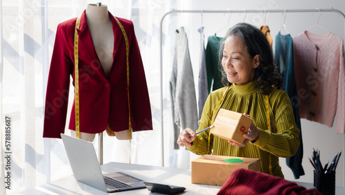 Elderly women are designers who make clothes, the owner of the shop, she is the owner of a female fashion clothing store and designs clothes and cutting the dress by herself, selling products online.