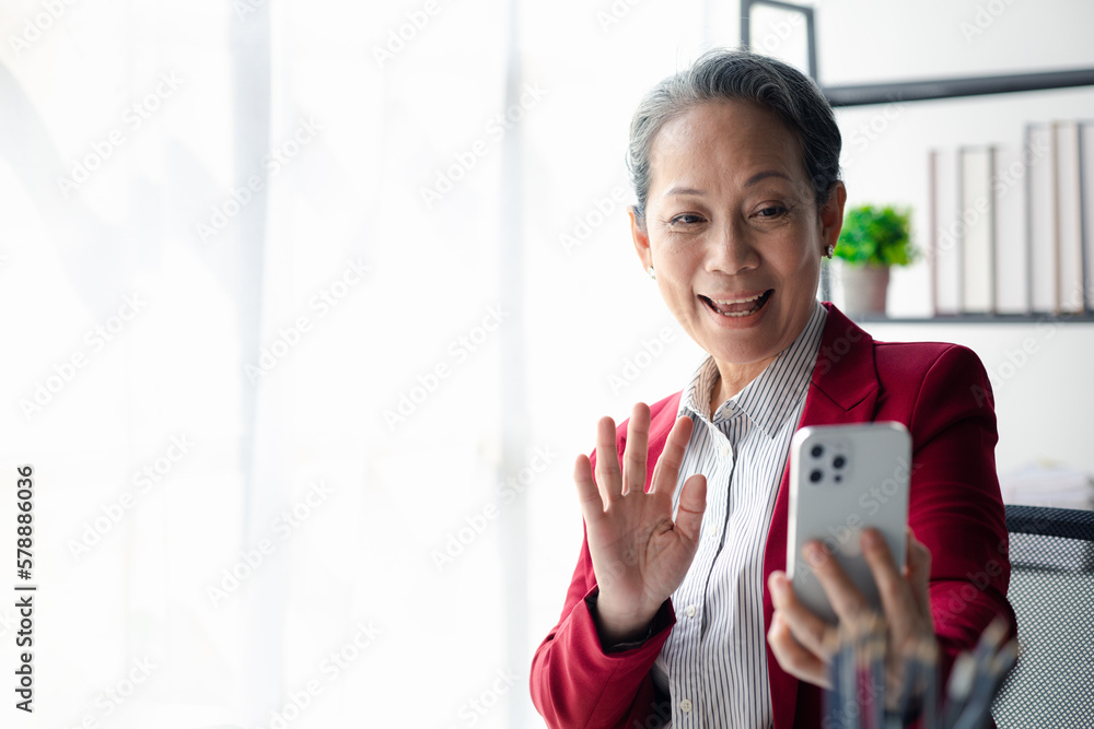Senior business woman in office and video call from phone, she is senior executive of company, business operation by senior senior woman, senior management work. Senior business woman in office and video call from phone, she is senior executive of company, business operation by senior senior woman, senior management work.