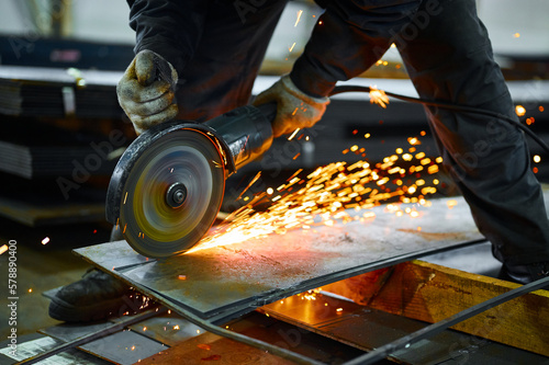 Schilderij op canvas Worker cuts metal with abrasive disk in plant workshop
