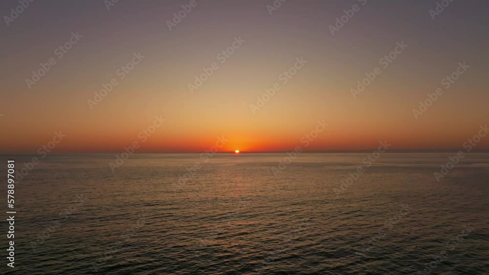 Aeril dolly towards a vibrant orange sunset over the coast of Iquique, Chile