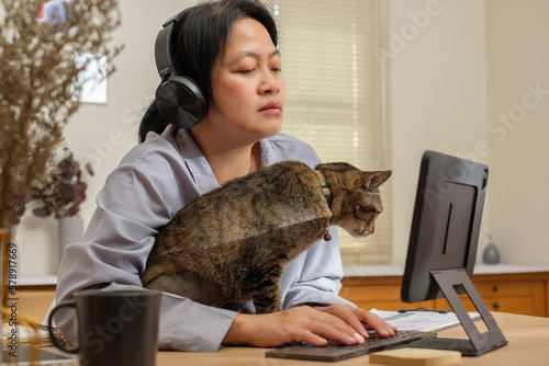asian woman working on tablet computer and hug her cat at home