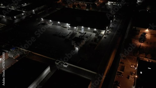 A nondescript industrial warehouse building is shown at night from an aerial, establishing view.