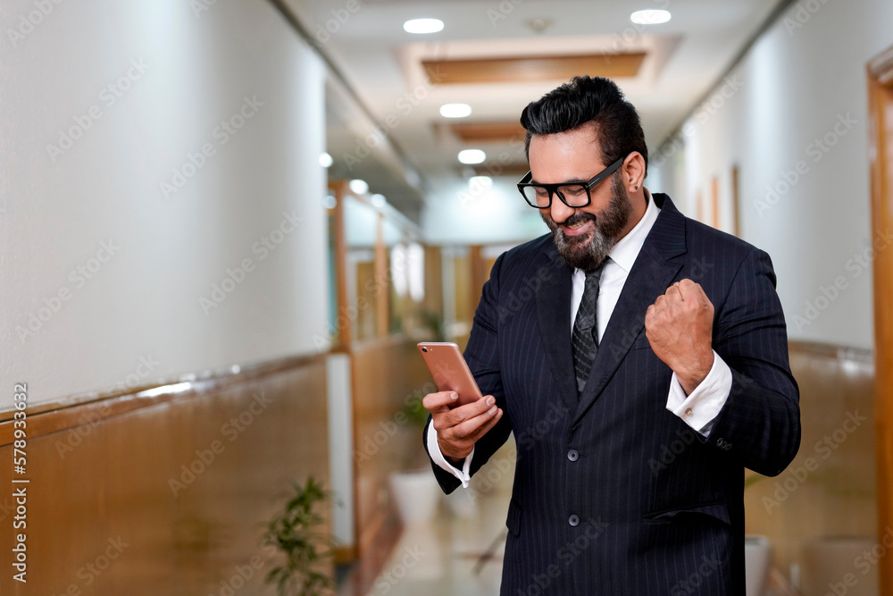 Indian corporate man smiling and winning expression after looking in smartphone some information. Indian corporate man smiling and winning expression after looking in smartphone some information.