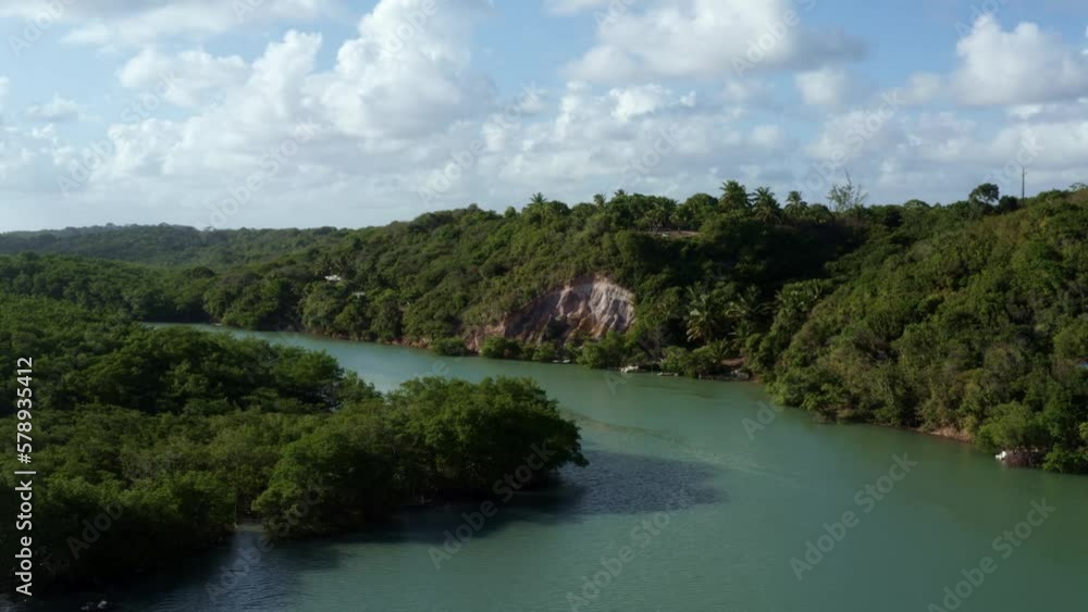 Dolly out aerial drone shot of the large winding tropical Gramame river with turquoise water surrounded by foliage and cliffs near the tropical beach capital city of Joao Pessoa in Paraiba, Brazil. Dolly out aerial drone shot of the large winding tropical Gramame river with turquoise water surrounded by foliage and cliffs near the tropical beach capital city of Joao Pessoa in Paraiba, Brazil.