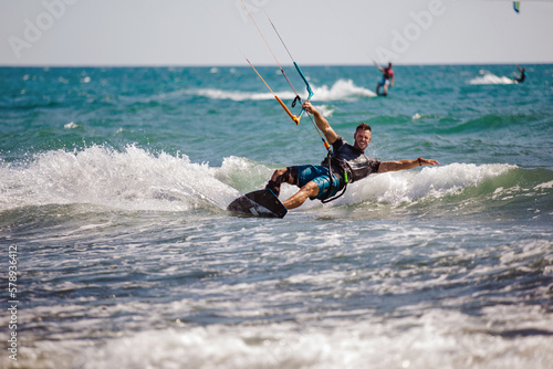 Professional kiter does the difficult trick. A male kiter rides against a beautiful background of waves and performs all sorts of maneuvers.